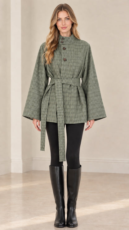 Front view of woman wearing sage green plaid belted cape jacket