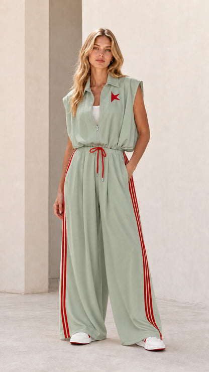 Front view of model wearing sage green sleeveless wide-leg track jumpsuit with red stripes