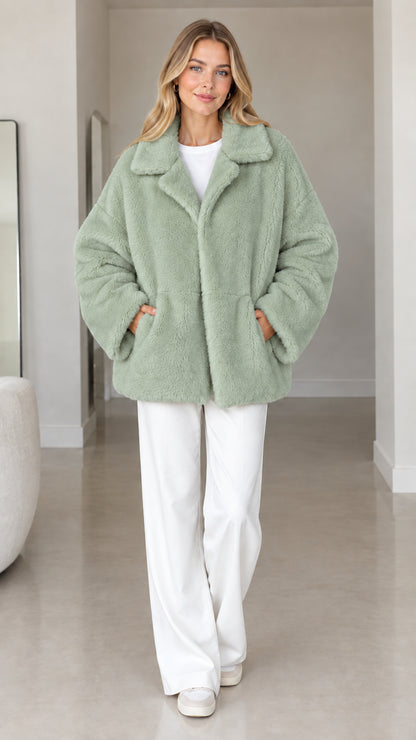 Front view of model wearing sage green plush faux fur lapel coat