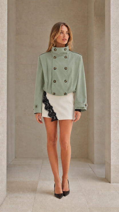 Front view of woman wearing sage green cropped double-breasted trench jacket