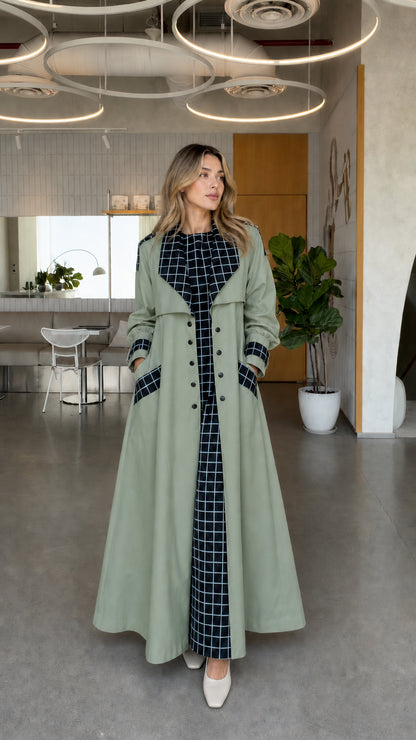 Full front view of model wearing sage green maxi trench coat with contrast grid accents
