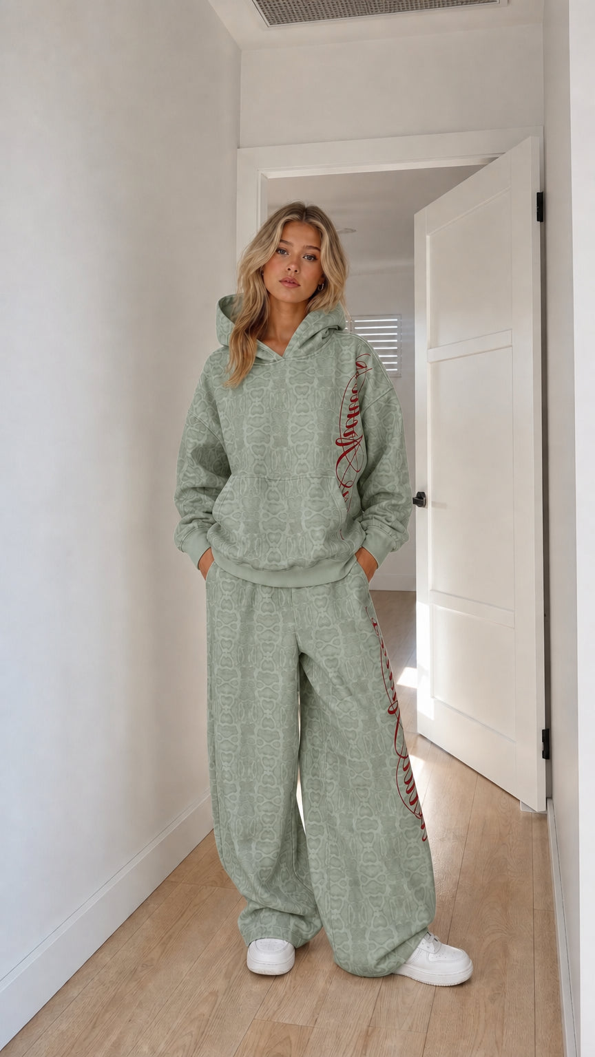 Model wearing sage green embossed monogram hoodie and wide-leg tracksuit set