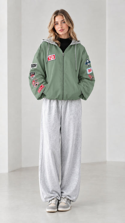 Front full view of sage green zip-up hooded bomber jacket with sleeve patches