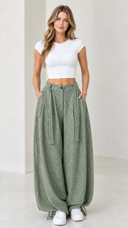 Front view of woman wearing sage green micro-plaid pleated wide leg pants