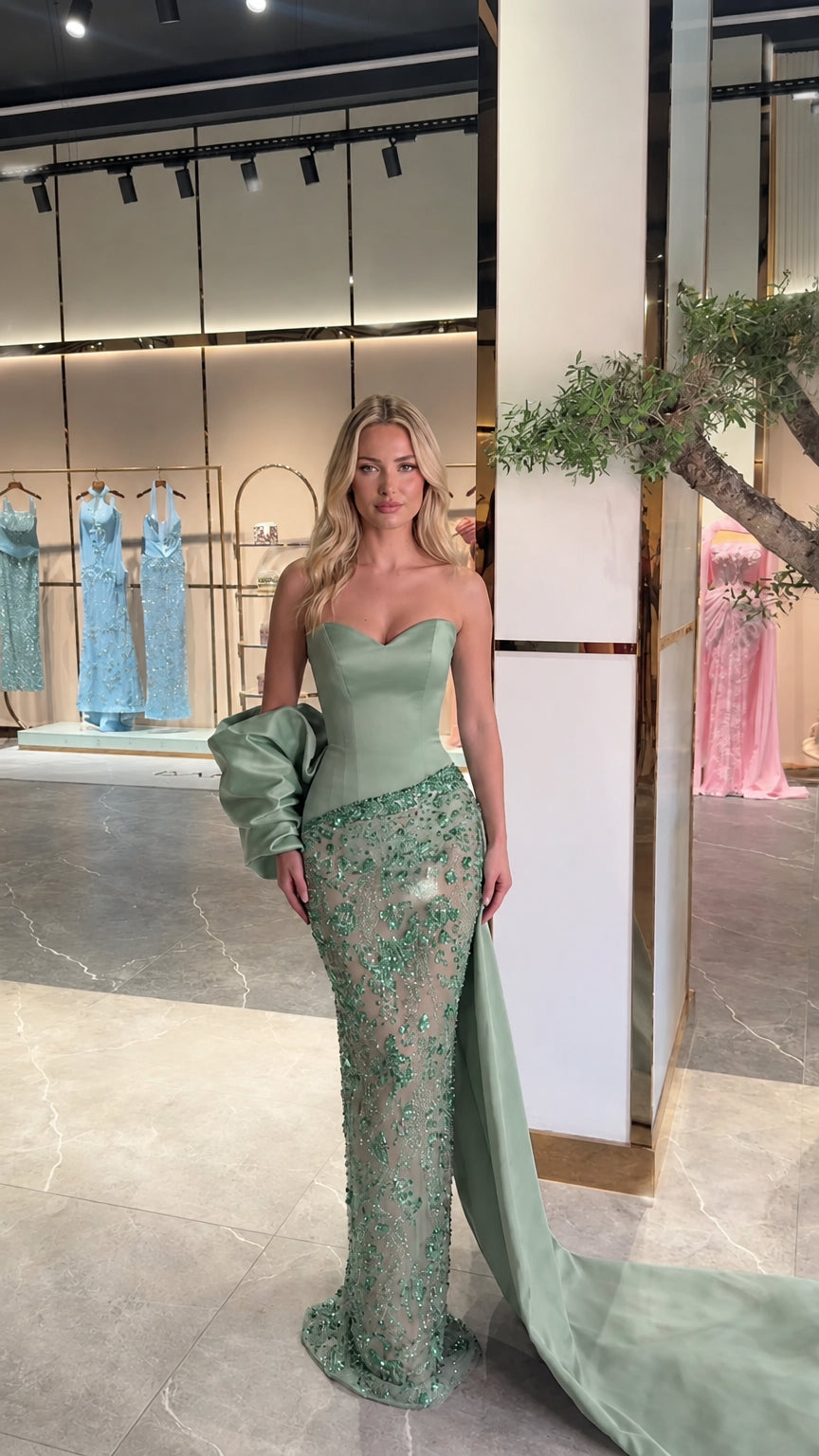 Model wearing sage green strapless crystal embellished evening gown with side train