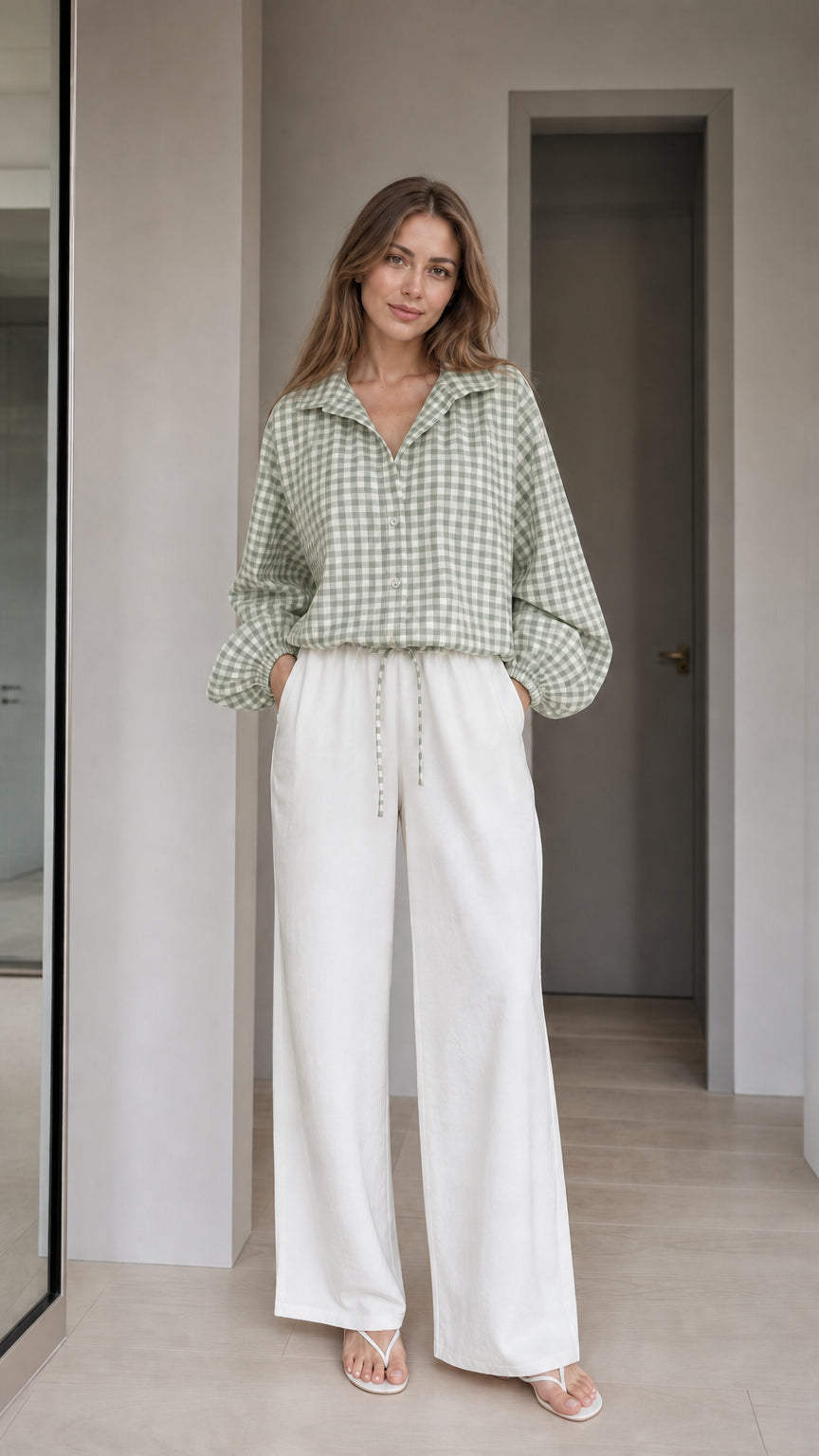 Woman wearing sage green gingham check blouse and white wide-leg trousers, front view