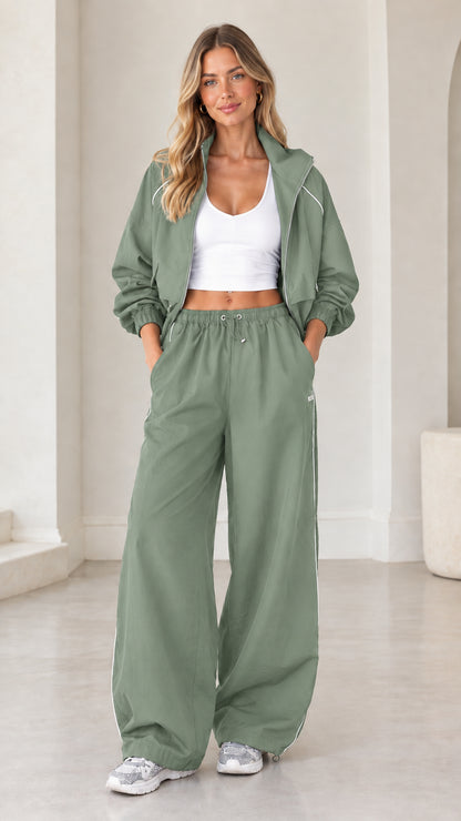 Model wearing sage green cropped zip tracksuit two-piece set with white contrast piping