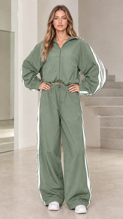 Front view of model wearing sage green hooded windbreaker tracksuit set with white side stripes