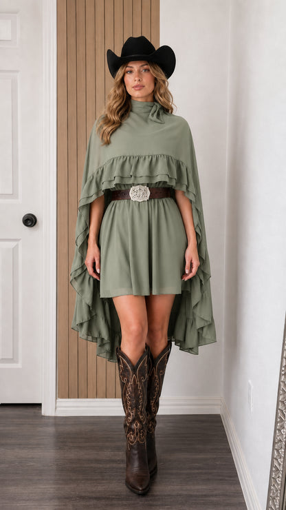 Front view of woman wearing sage green mock neck ruffle cape mini dress