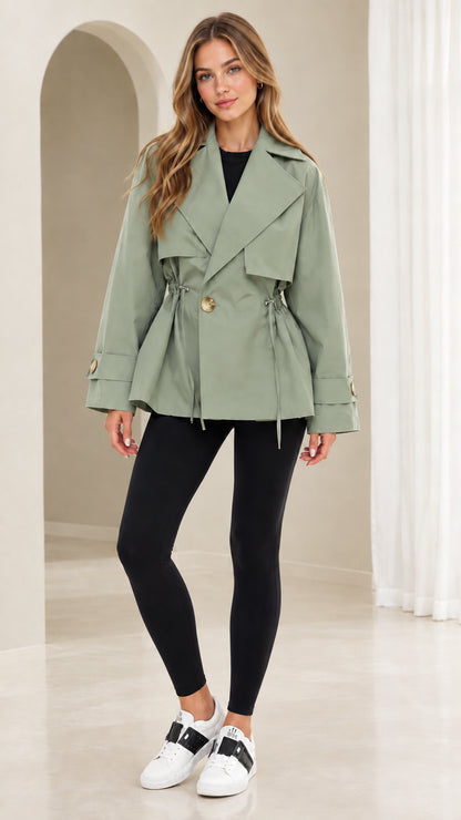 Front view of model wearing sage green short drawstring trench jacket