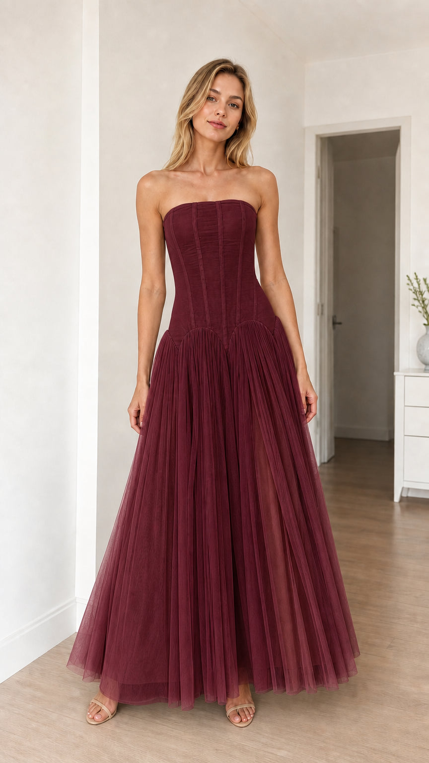 Model wearing burgundy strapless corset tulle maxi dress