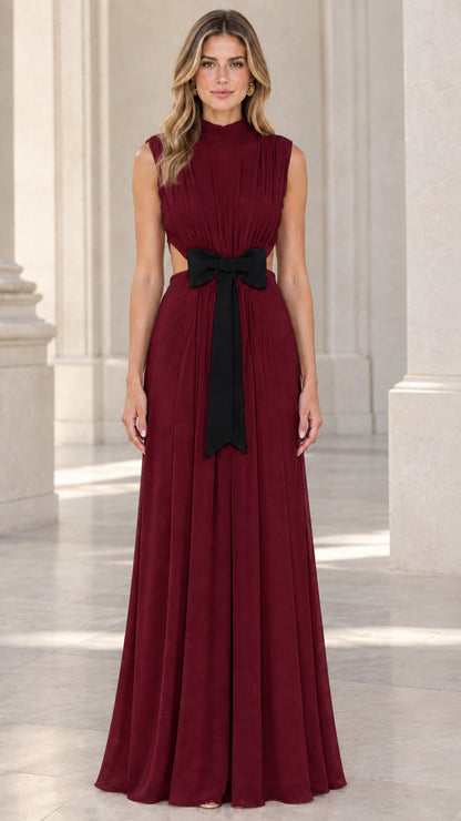 Front view of model wearing burgundy wine red pleated formal dress with black bow