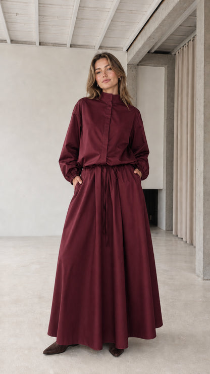 Front full view of woman wearing burgundy stand collar drawstring maxi dress
