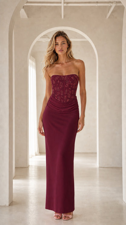 Model wearing burgundy strapless corset maxi evening gown