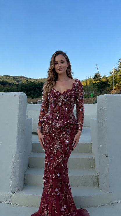 Model wearing the floral appliqué corset peplum evening gown in burgundy