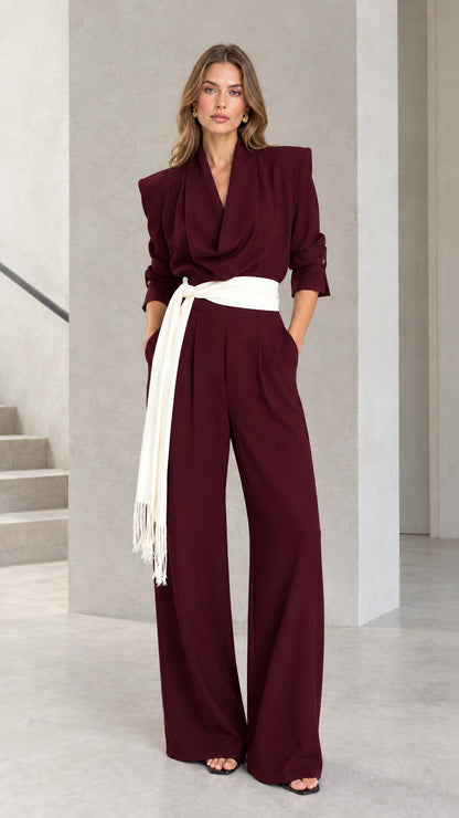 Front view of woman wearing Burgundy wine draped wide leg jumpsuit with fringe belt