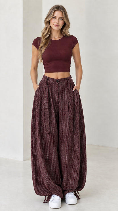 Front view of woman wearing burgundy wine red micro-plaid balloon pants