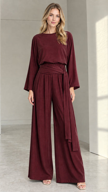 Front full view of woman wearing burgundy wine long-sleeve wide-leg jumpsuit