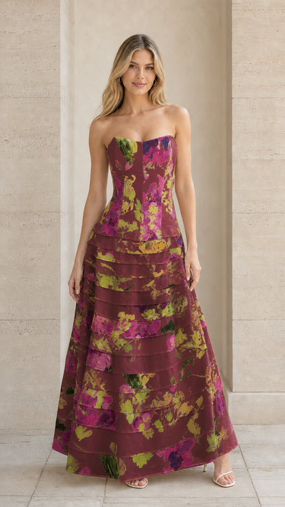 Model wearing burgundy floral strapless tiered formal evening dress