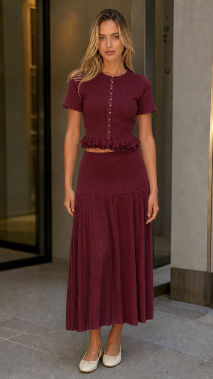 Front view of model wearing burgundy knit top and pleated midi skirt set