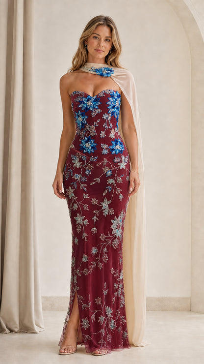 Model wearing burgundy floral sequin strapless maxi gown with cape
