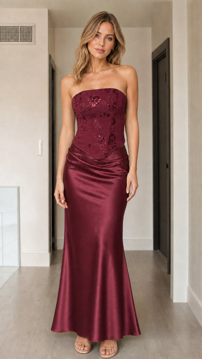 Front view of woman wearing burgundy strapless sequin corset satin maxi dress