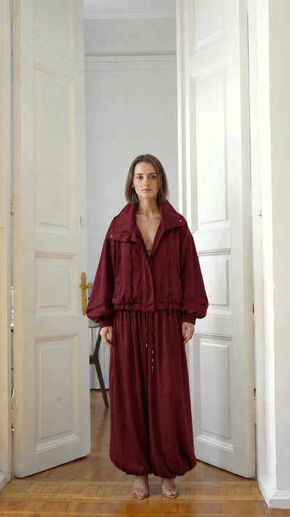 Front view of model wearing burgundy red two-piece jacket and balloon pants set