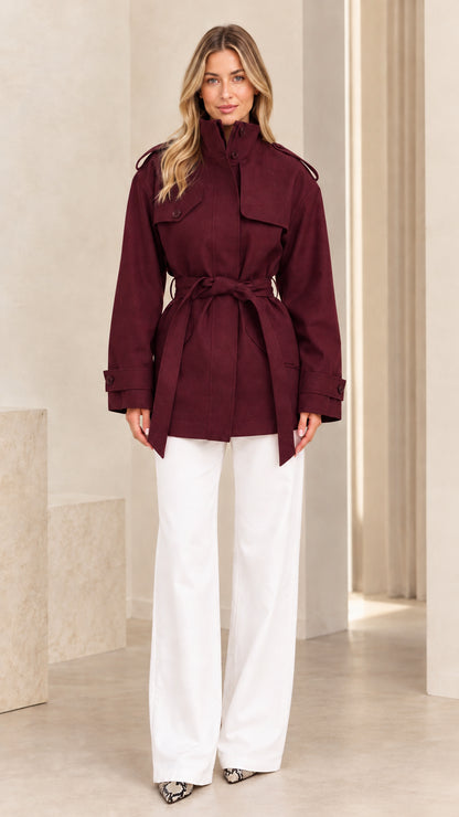 Front view of model wearing burgundy high neck belted short trench coat