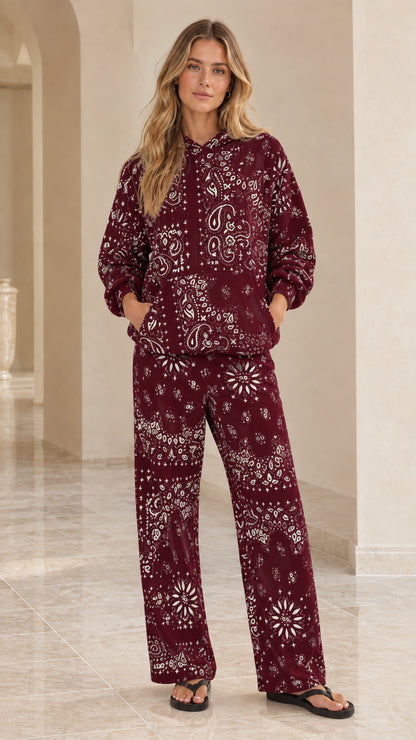 Full-body view of woman wearing burgundy bandana print hoodie and wide-leg pants set