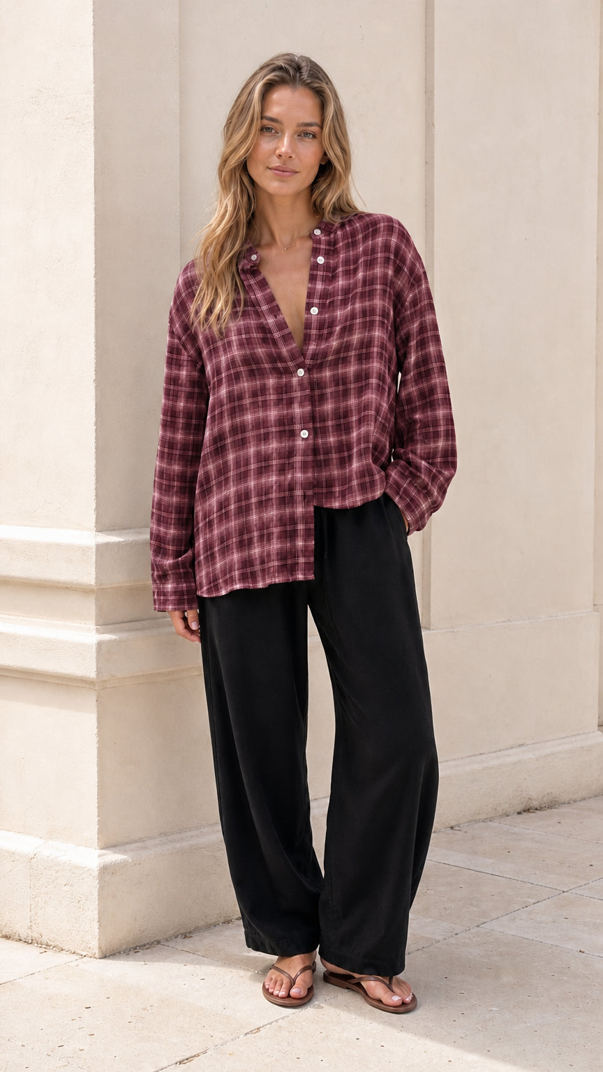 Model wearing burgundy plaid button-down blouse with black trousers