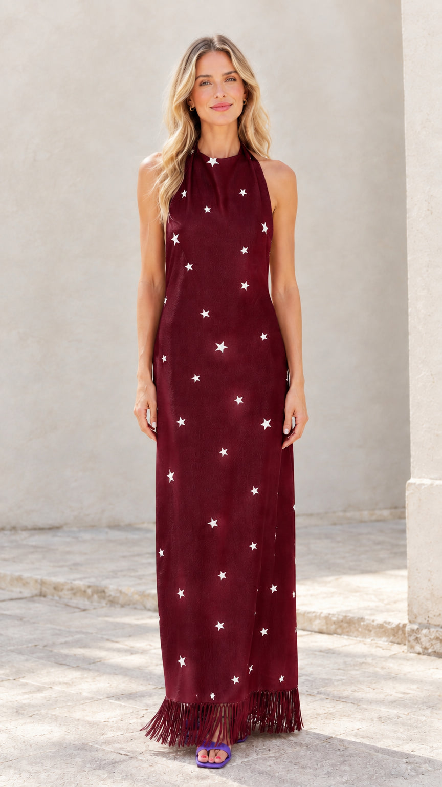 Woman wearing burgundy star print halter maxi dress with fringe hem