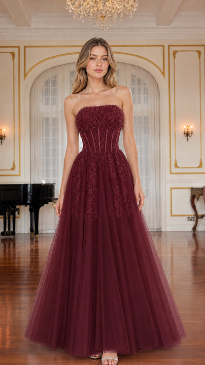 Model wearing burgundy red strapless corset tulle evening gown