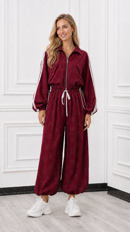 Front view of woman wearing a burgundy red zip-front track jumpsuit with white side stripes