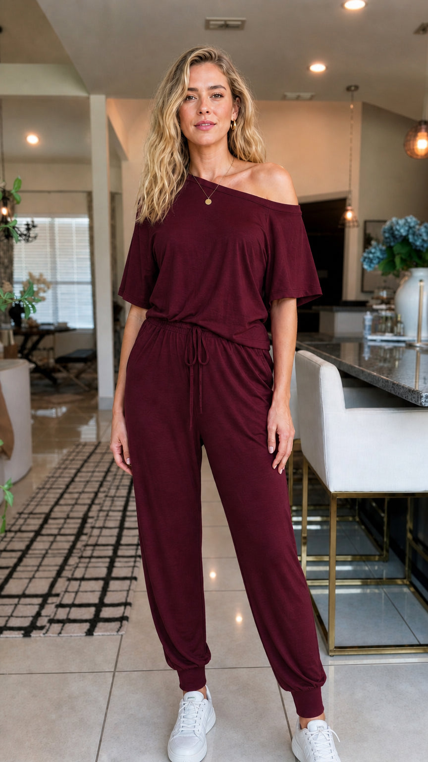 Front view of woman wearing burgundy off-the-shoulder jumpsuit