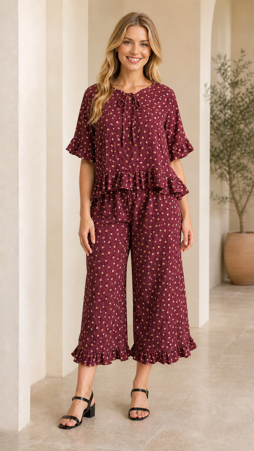 Front view of model wearing burgundy floral tie-neck ruffle top and pants set