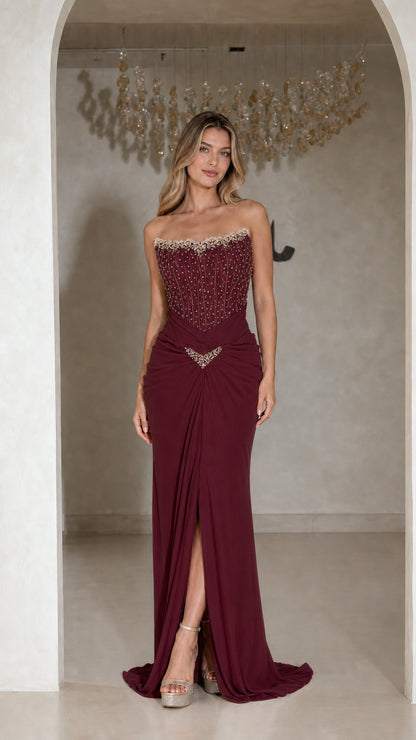 Front view of strapless burgundy red beaded corset evening gown with front slit