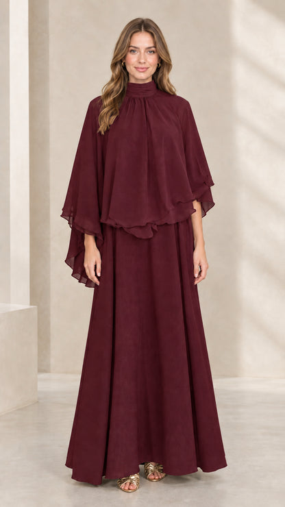Front view of woman wearing burgundy mock neck capelet maxi dress