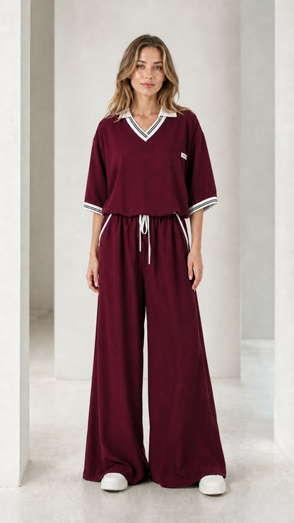 Front view of a burgundy women's wide-leg jumpsuit with contrast striped trim