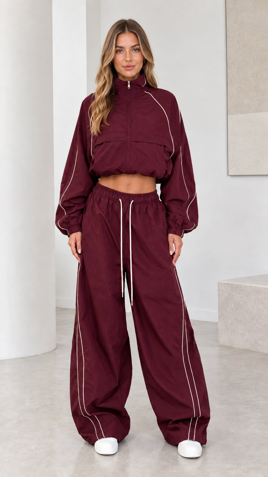 Front view of model wearing burgundy cropped windbreaker and parachute pants set