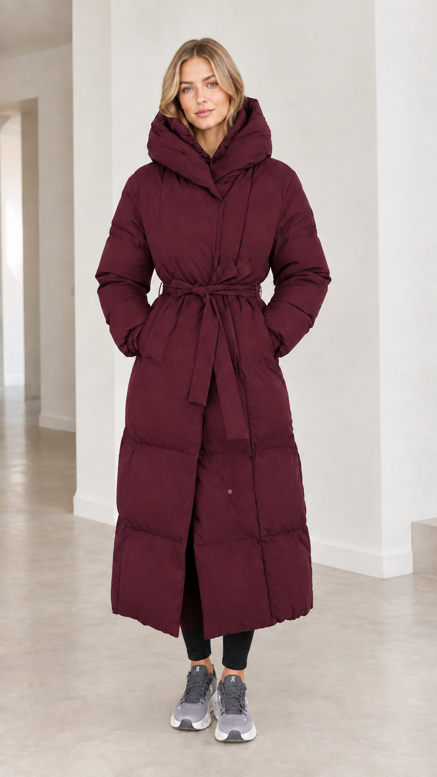 Front view of model wearing deep burgundy red long belted puffer parka