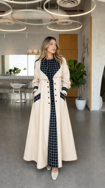 Full front view of model wearing beige cream maxi trench coat with black grid contrast trim