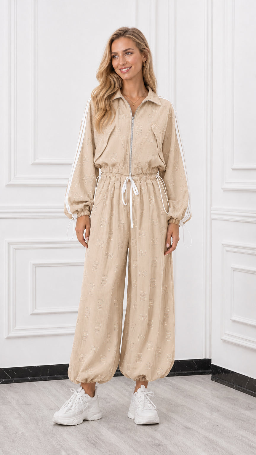 Front view of woman wearing a beige neutral long sleeve track jumpsuit