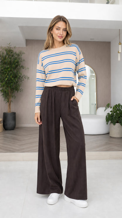 Model wearing beige and blue striped cropped knit sweater with dark wide-leg pants