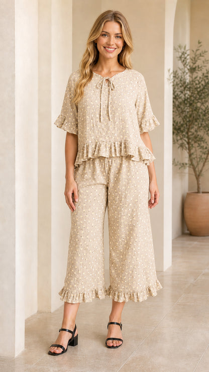 Front view of model wearing beige floral tie-neck ruffle top and cropped pants set