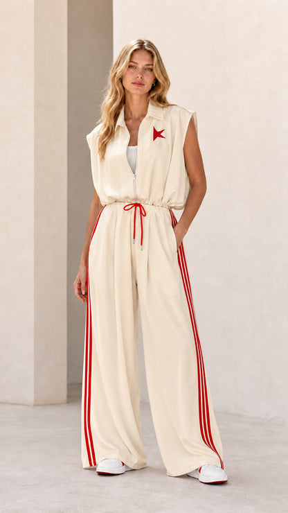Front view of model wearing cream sleeveless wide-leg track jumpsuit with red stripes