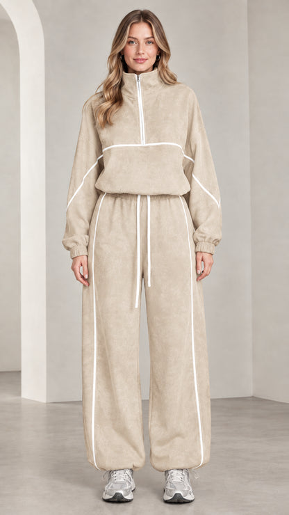 Front view of woman wearing beige quarter-zip tracksuit set with white contrast piping