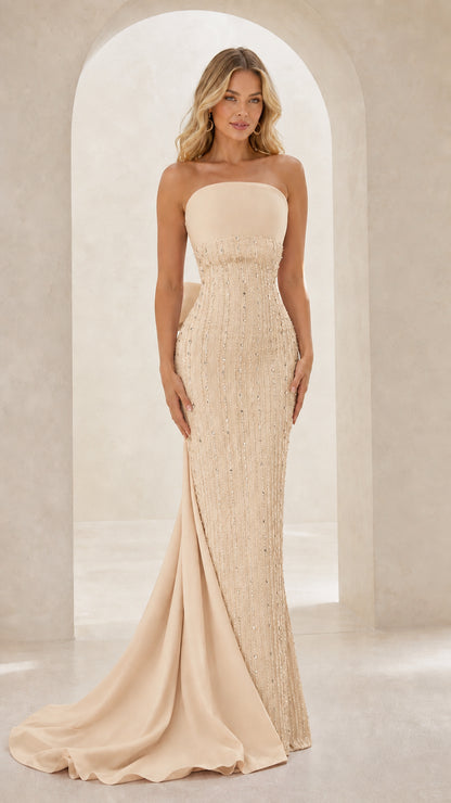 Model wearing strapless beaded evening gown with back train in champagne