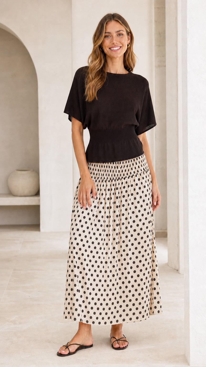 Front full-length view of black knit bodice and cream polka dot skirt dress