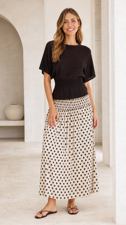 Front full-length view of black knit bodice and cream polka dot skirt dress