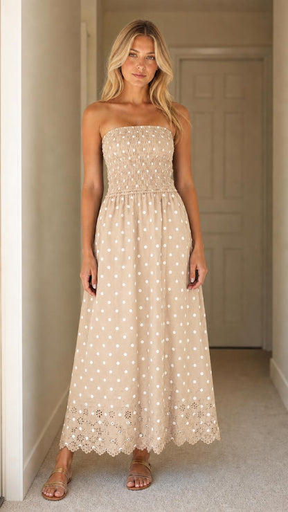 Front view of woman wearing beige polka dot strapless maxi dress